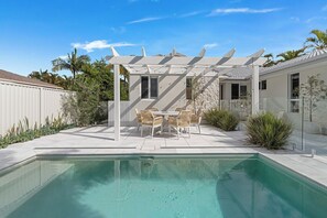 Ein Pool mit Pergola und einer Sitzgruppe im Freien.
