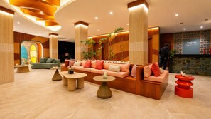 Eine moderne Lobby mit einer gebogenen Rezeption, einer Sitzecke und einer großen Wand mit dem Schriftzug 'wave'.