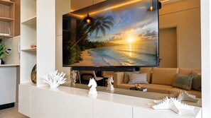 Ein modernes Wohnzimmer mit großem Flachbildfernseher an der Wand, einer Couch, einem Couchtisch und Dekorationselementen.