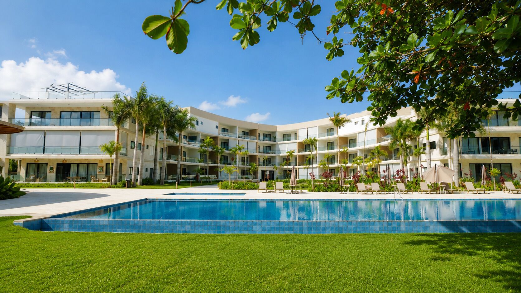 Ein Hotel mit Schwimmbad, mehreren Balkonen und Palmen.