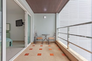 A balcony with a small table and two chairs, a television mounted on the wall, and a patterned floor. - The 1 Bedroom "Six" Apartment with sea view and Olympic pool (Muang Pattaya)