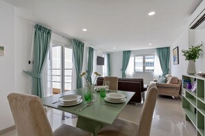 A dining area with a table set for two, a sofa, and a bookshelf. - The 1 Bedroom "Six" Apartment with sea view and Olympic pool (Muang Pattaya)