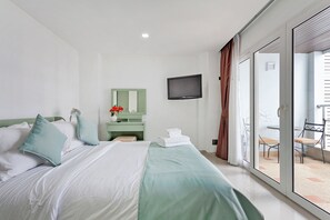 A hotel room with a bed, a television, a bathroom mirror, and a sliding glass door to the outside. - The 1 Bedroom "Six" Apartment with sea view and Olympic pool (Muang Pattaya)