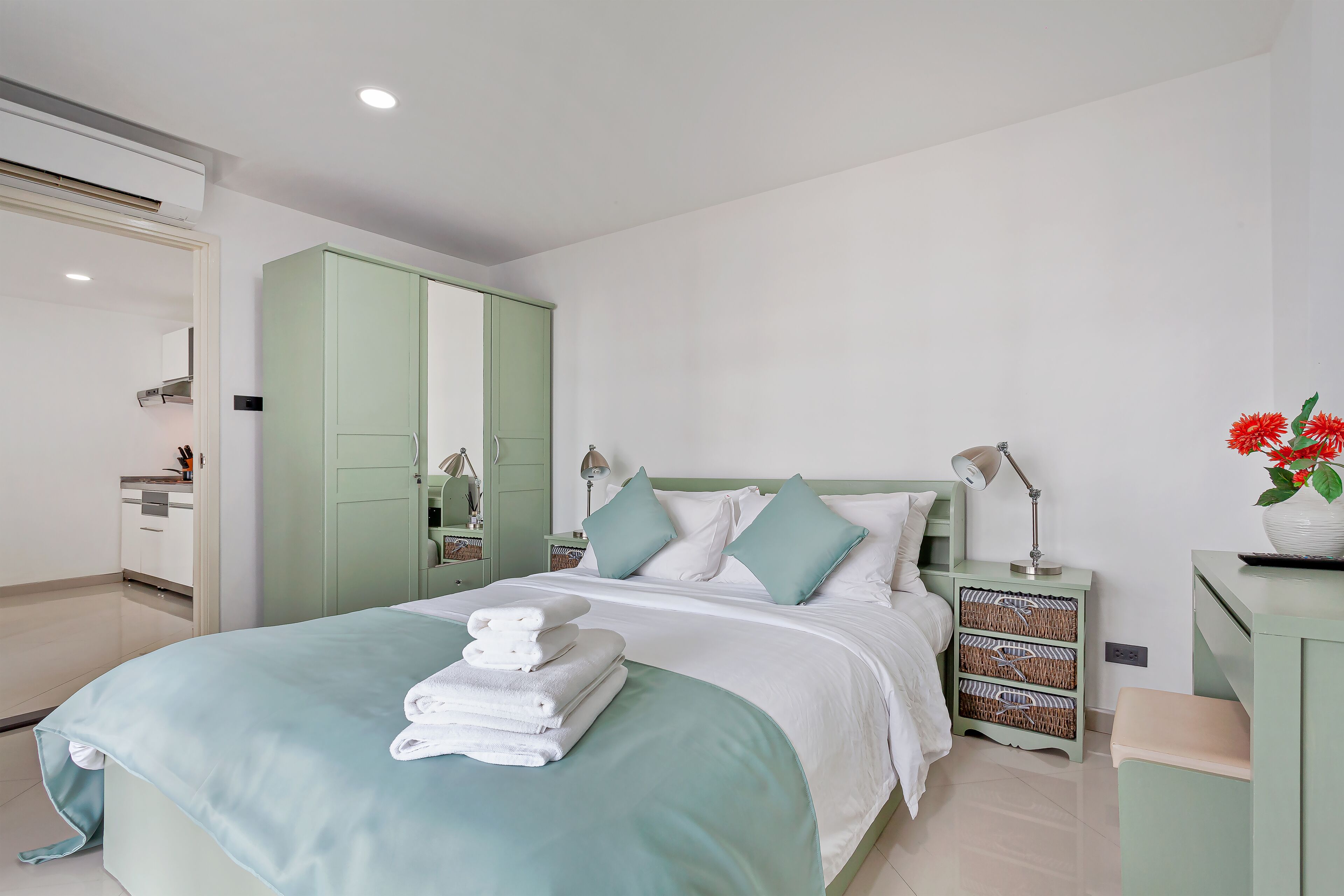 Un dormitorio ordenado con cama, mesitas de noche, un armario y una mesilla.