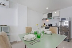 A modern kitchen with a dining area set for a meal. - The 1 Bedroom "Six" Apartment with sea view and Olympic pool (Muang Pattaya)