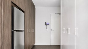A hallway with a modern kitchen area, including a refrigerator and a door with a security keypad. - Upper West Side by Ready Set Stay (Melbourne)