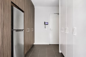 A hallway with a modern kitchen area, including a refrigerator and a door with a security keypad. - Upper West Side by Ready Set Stay (Melbourne)