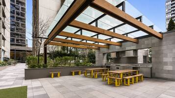 An outdoor patio with wooden benches and a modern kitchen area.