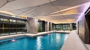 An indoor swimming pool with clear water, surrounded by modern architecture and glass walls. - Upper West Side by Ready Set Stay (Melbourne)