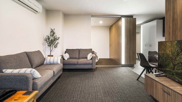 A modern living room with a sofa, a smaller couch, a coffee table, and a TV on a wooden cabinet. - Upper West Side by Ready Set Stay (Melbourne)