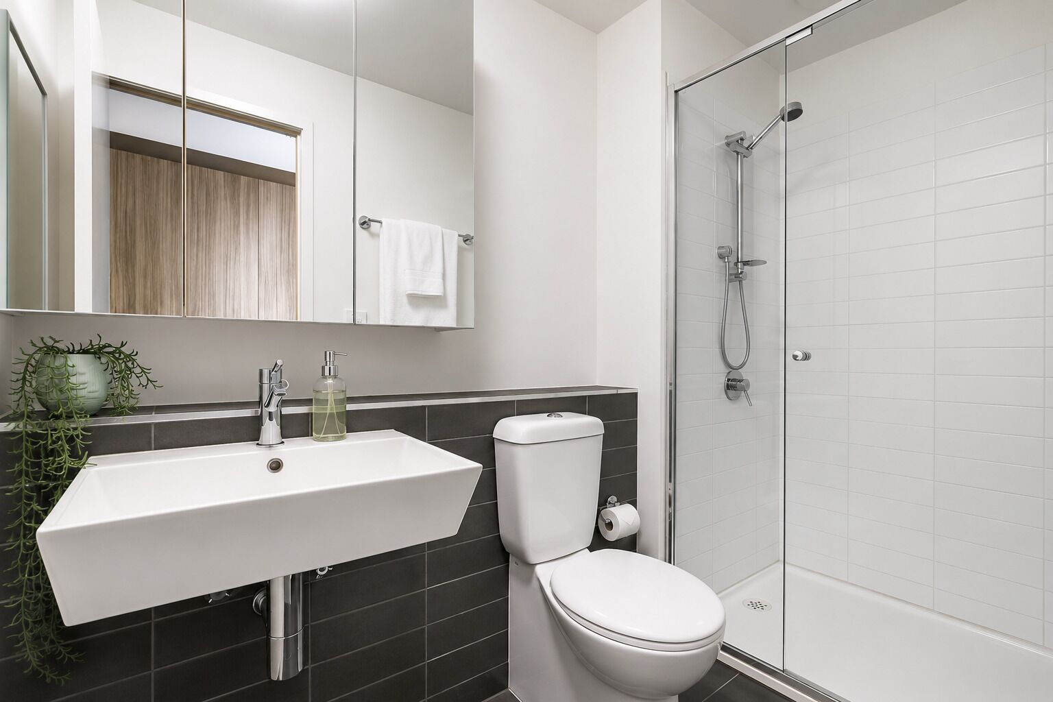 A modern bathroom with a white sink, a toilet, and a glass-enclosed shower.