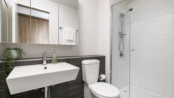 A modern bathroom with a white sink, a toilet, and a glass-enclosed shower.