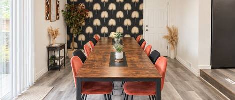 A dining room with a long wooden table, red chairs, and a black and white patterned wall.