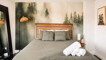 Ein Schlafzimmer mit Bett, Kopfstütze, Wandgemälde, Lampe und einem gerahmten Bild.