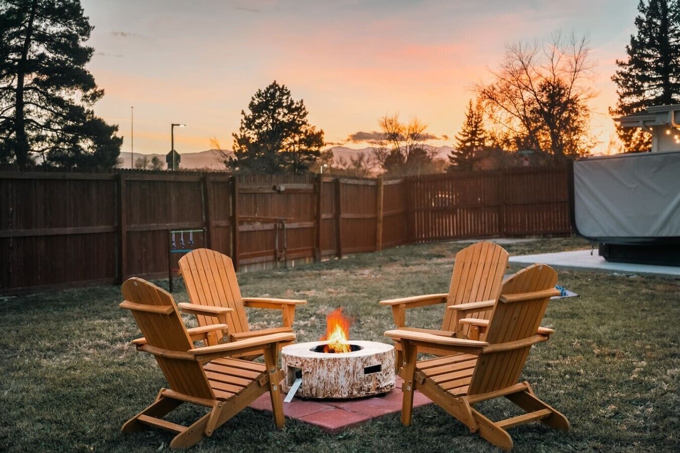An outdoor seating area with two Adirondack chairs around a circular fire pit.