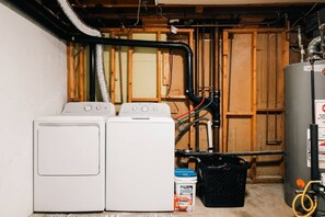 Ein Waschraum mit zwei Waschmaschinen, einem Warmwasserbereiter und einer Wasserpumpanlage.