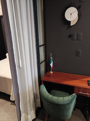 Ein Zimmer mit einem Bett, einem Schreibtisch mit einer Flagge, einer Uhr und einem Stuhl.