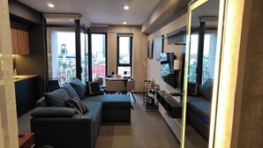 Una sala de estar moderna con un sofá modular, un comedor y un televisor grande.
