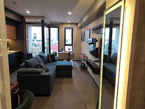 Ein modernes Wohnzimmer mit einem Ecksofa, einem Essbereich und einem großen Fernseher.