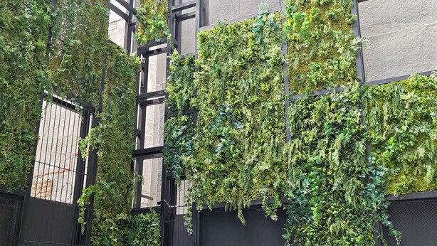 Un edificio con jardines verticales y un camino de grava.
