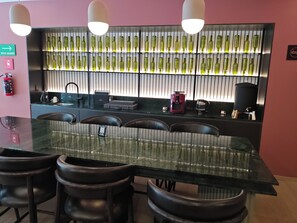 A bar area with a long table, multiple chairs, and a wall-mounted shelf with bottles. - Balcony with a view of the Monument to the Revolution, Rooftop, and Gym (Ciudad de México)