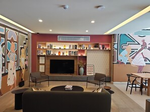 A modern living room with a flat-screen TV, seating area, and a bookshelf with books and decorative items. - Balcony with a view of the Monument to the Revolution, Rooftop, and Gym (Ciudad de México)