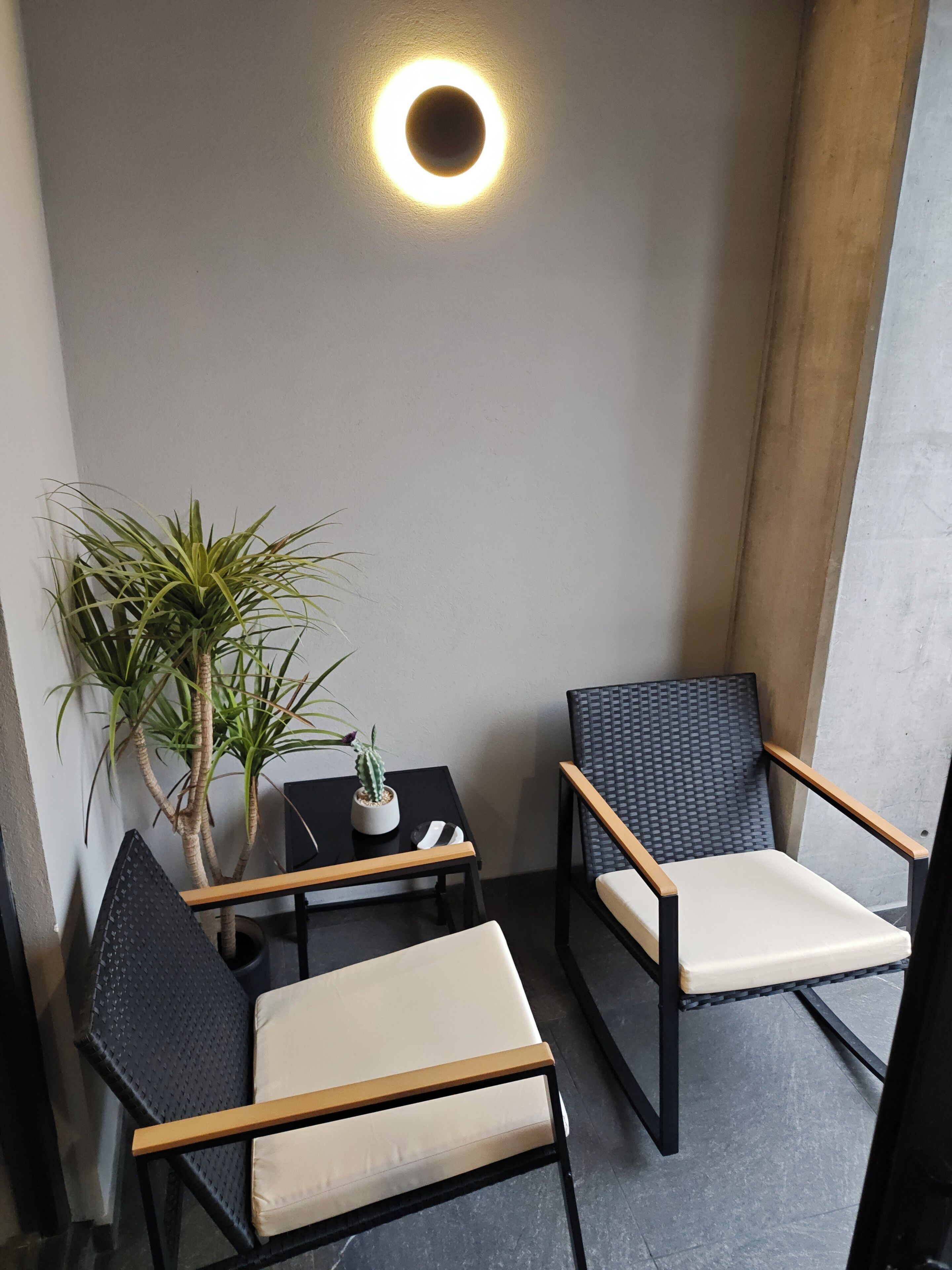 A small seating area with two chairs and a table, a potted plant, and a wall-mounted light fixture.