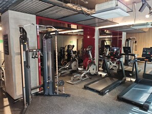 Ein Fitnessstudio mit unterschiedlichen Trainingsgeräten, darunter Laufbänder, ein Kraftgerät und ein Ergometer.