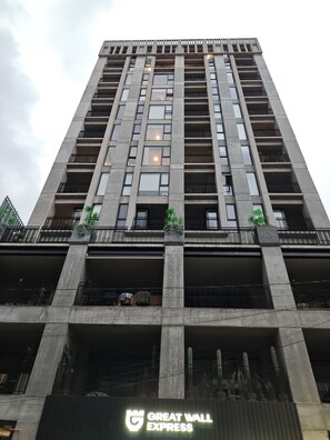 Un grand immeuble moderne, doté de nombreux balcons et d’une enseigne bien visible, « GREAT WALL EXPRESS », située en bas.