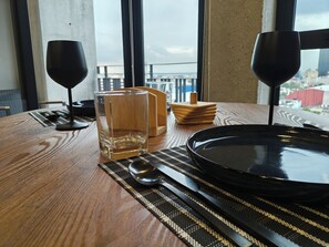 Ein Esstisch mit einem Glas, einem Löffel, einem schwarzen Teller und zwei Weingläsern.