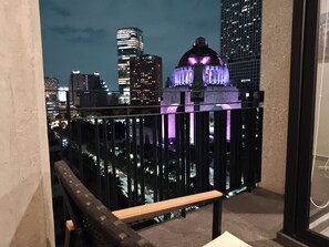 A balcony with a view of a cityscape at night, including illuminated buildings and a dome structure.
