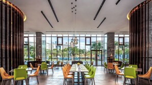 Un comedor amplio con techos altos y ventanas grandes, que ofrece vistas de los edificios y espacios verdes circundantes.