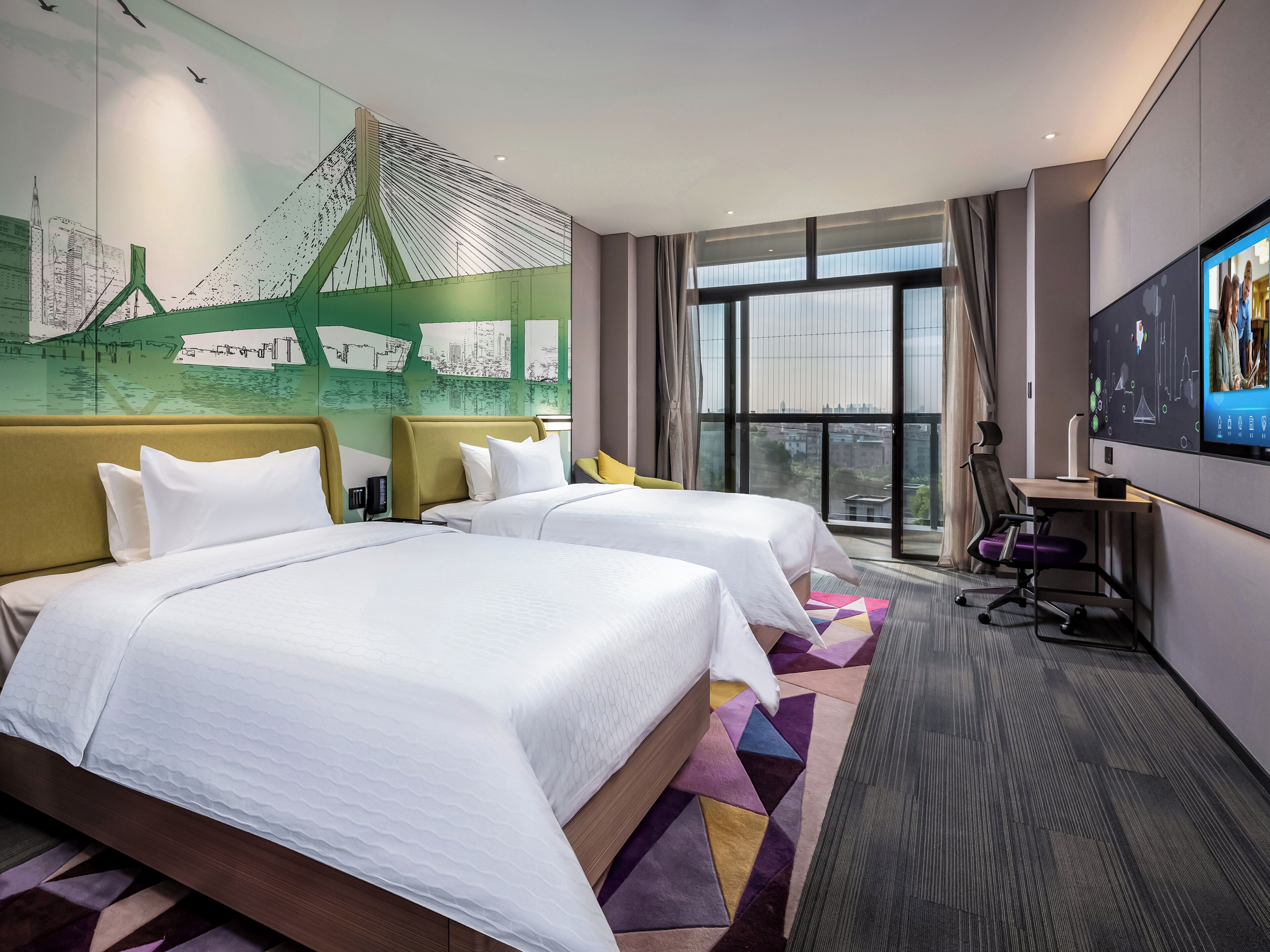 Habitación de hotel con dos camas, un escritorio, televisión y un amplio ventanal con vista a la ciudad.