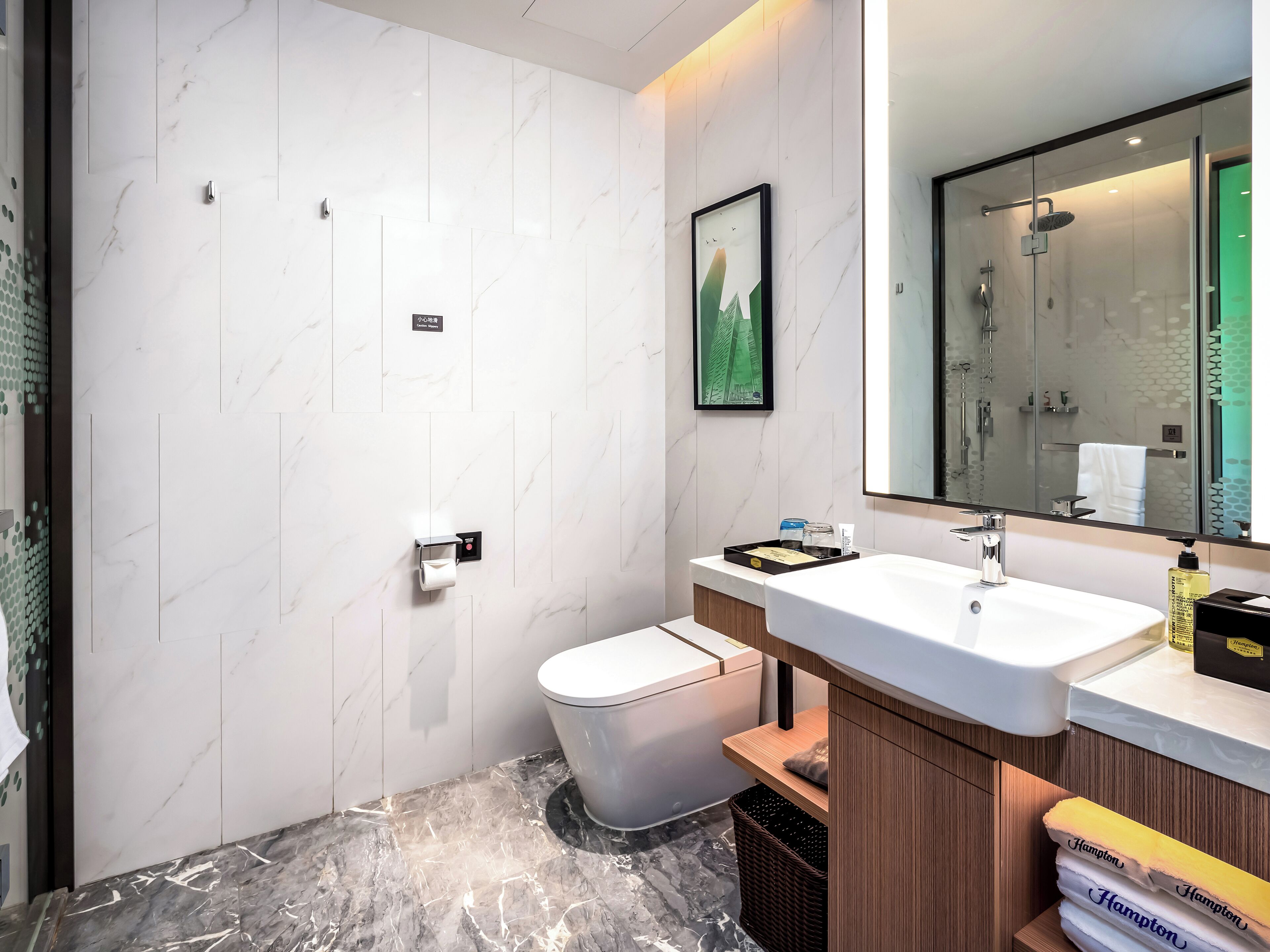 Une salle de bain moderne avec un mur en marbre blanc, des toilettes, un lavabo avec un miroir et un espace douche.