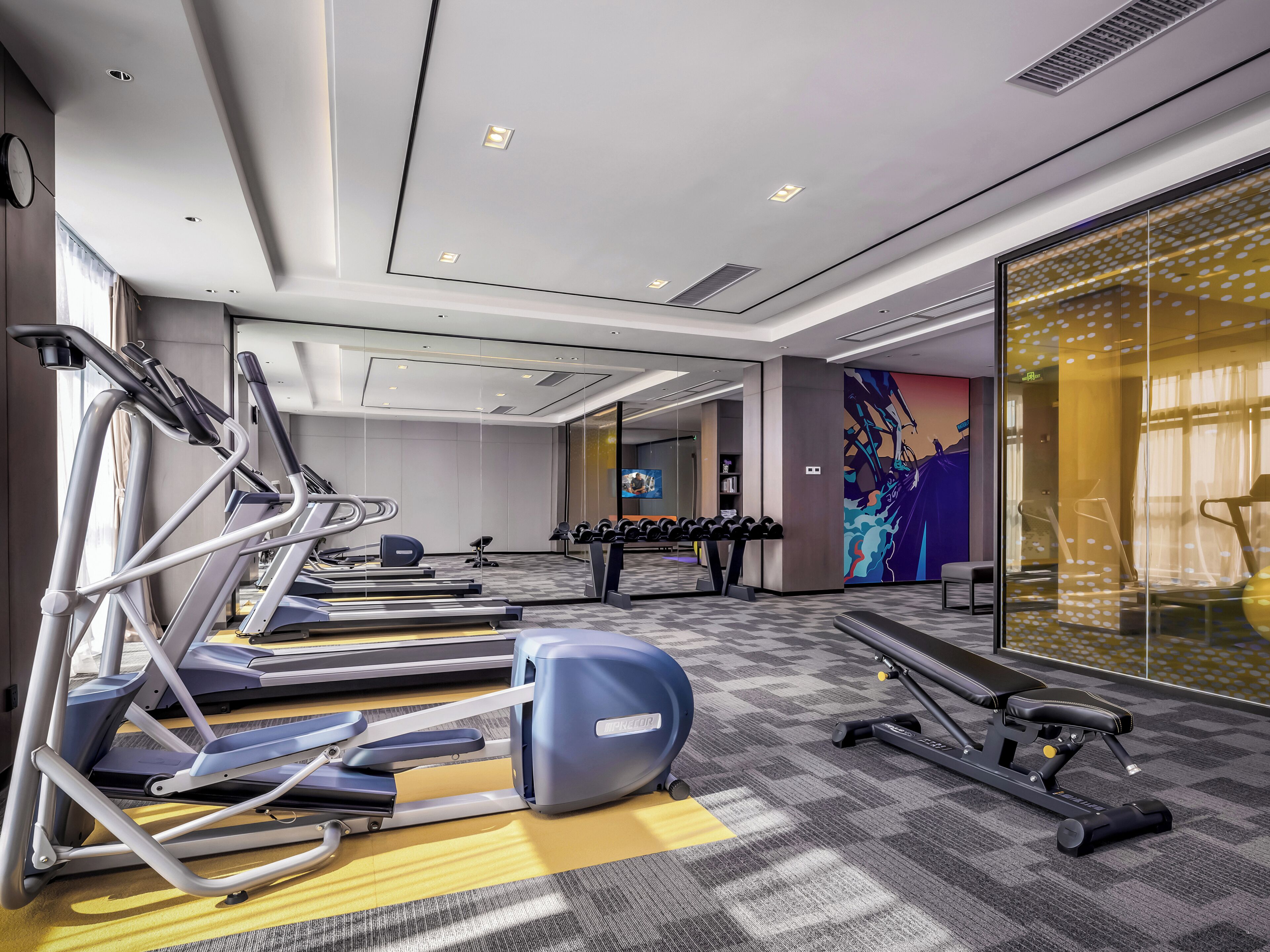 A modern gym with treadmills, elliptical machines, and free weights.