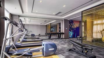 A modern gym with treadmills, elliptical machines, and free weights.
