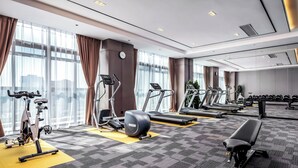 Un gimnasio moderno con equipo de ejercicio, ventanas amplias y piso alfombrado.