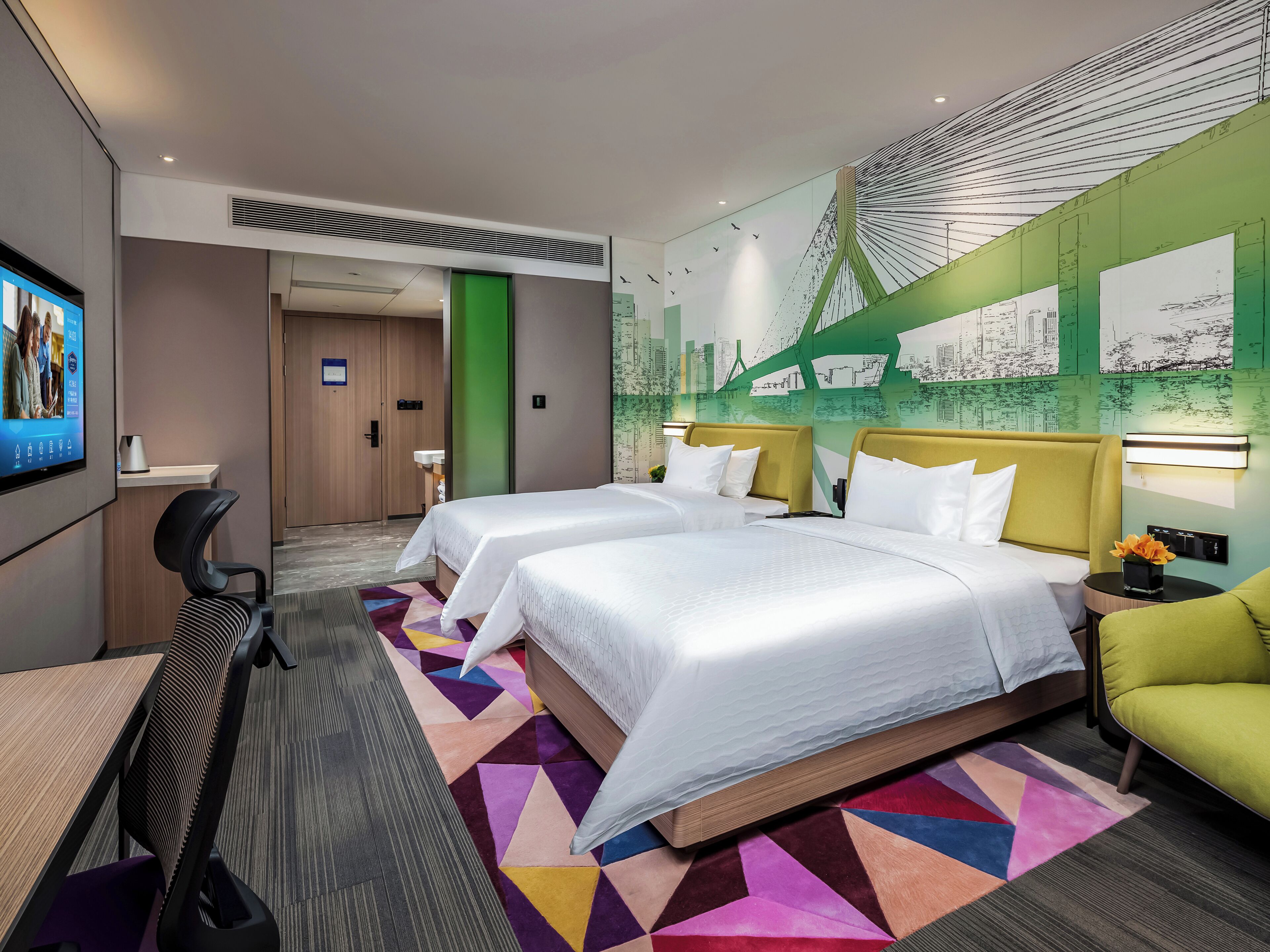 A hotel room with two beds, a desk, a chair, and a TV.
