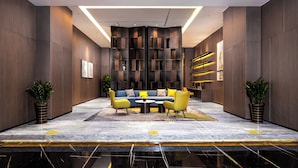 Un vestíbulo moderno con una zona de estar central, un muro decorativo y un suelo de mármol.