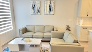 A living room with a sofa, a coffee table, and abstract art on the wall. - New 4-Bedroom Home | Modern Comfort in NE Calgary—Beautiful and Affordable (Calgary)