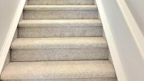 A carpeted staircase with white walls and a fire extinguisher mounted on the wall. - New 4-Bedroom Home | Modern Comfort in NE Calgary—Beautiful and Affordable (Calgary)