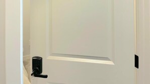 A white door with the number 1, a keyhole, and a door handle. - New 4-Bedroom Home | Modern Comfort in NE Calgary—Beautiful and Affordable (Calgary)