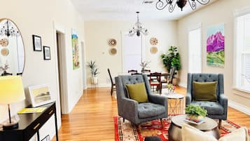 A spacious living room with a dining area, hardwood flooring, and modern furniture.