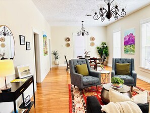 A spacious living room with a dining area, hardwood flooring, and modern furniture.