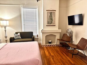 Une chambre d’hôtel équipée d’un lit, d’un canapé, d’une télévision, d’une cheminée et d’un ventilateur.