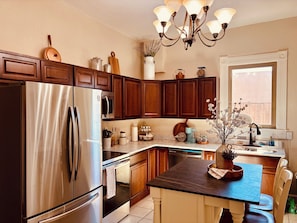 A modern kitchen with stainless steel appliances, wooden cabinets, and a central island with seating.