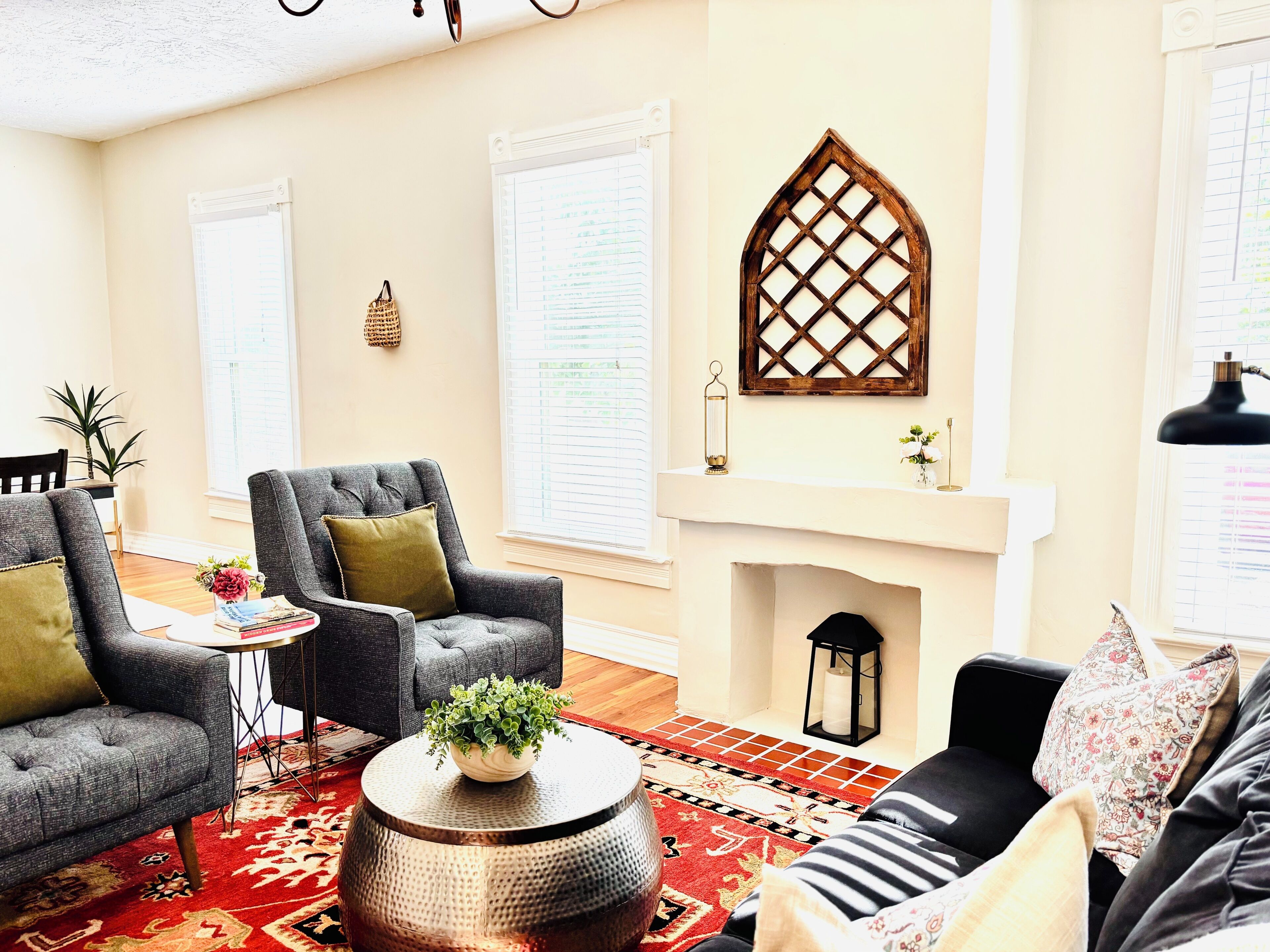 A living room with two armchairs, a sofa, a fireplace, and a decorative wall piece.