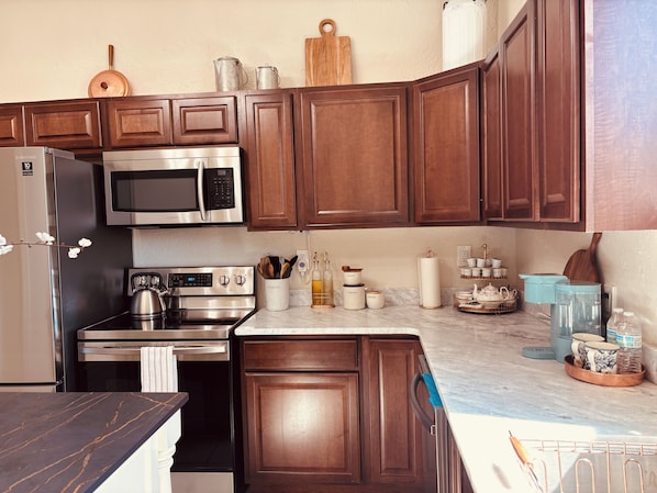 Una cocina moderna con armarios de madera, electrodomésticos de acero inoxidable y encimera de mármol.
