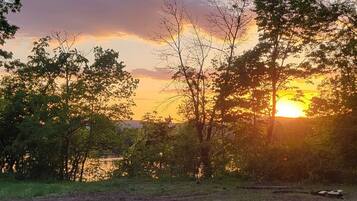 A sunset over a body of water with trees in the foreground.