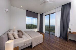 Ein modernes Schlafzimmer mit einem großen Bett, Blick ins Freie und Holzboden.
